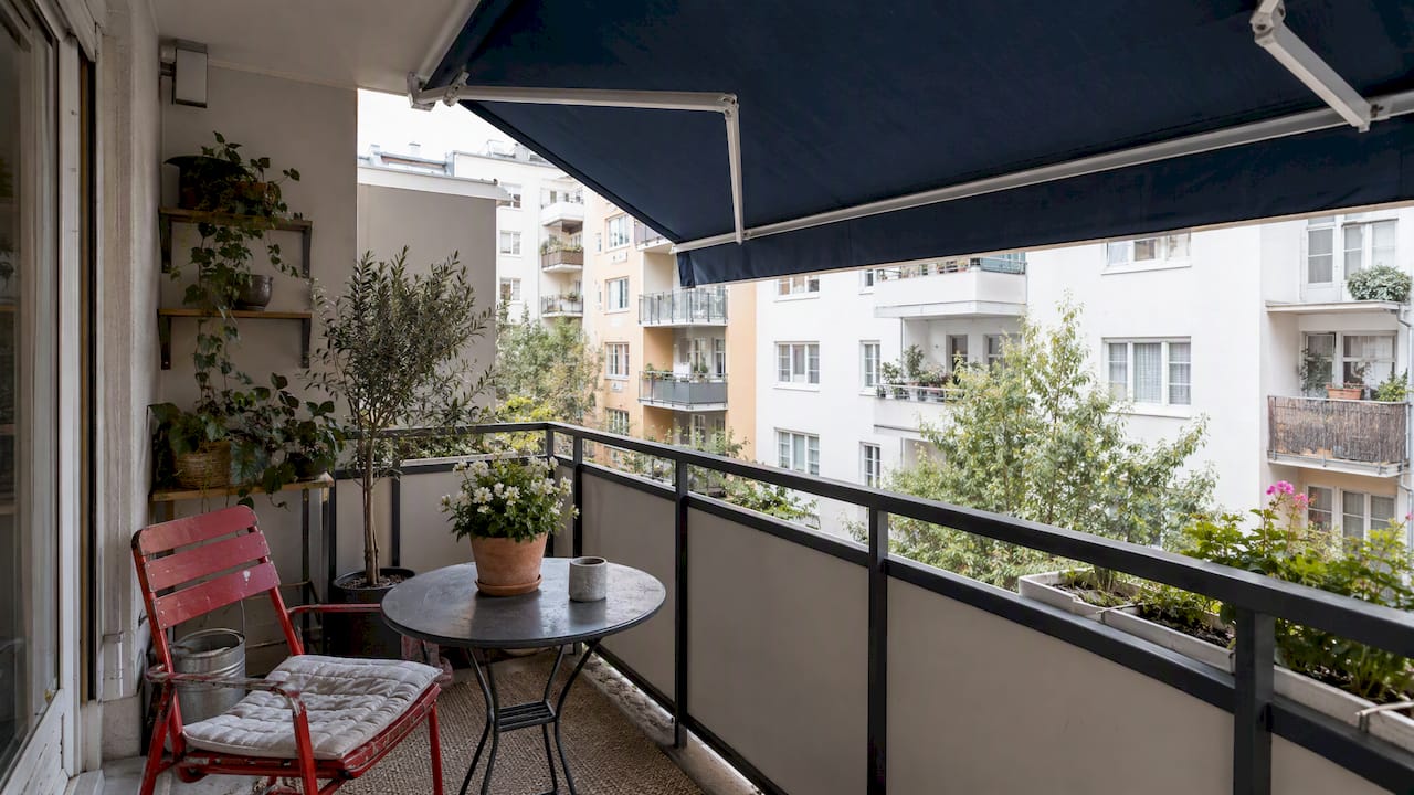 Kihúzott napellenző ad árnyékot egy városi erkélyen